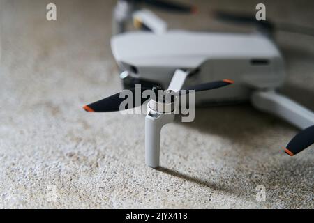 Small gray quadcopter on a gray background. Quadrocopter close-up. Stock Photo