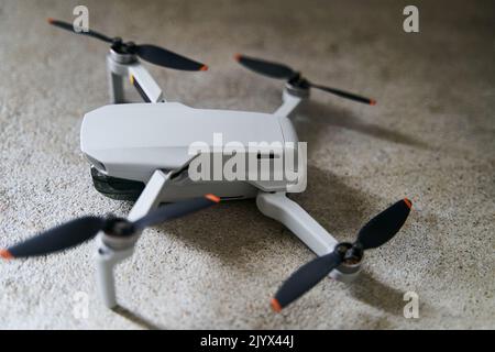 Small gray quadcopter on a gray background. Quadrocopter close-up. Stock Photo