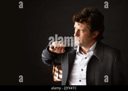 Well suited to his profession. a well dressed businessman carrying a bag against a dark background. Stock Photo