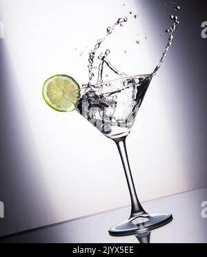 Cocktail glass with juice, lime and ice on a white gradient background Stock Photo