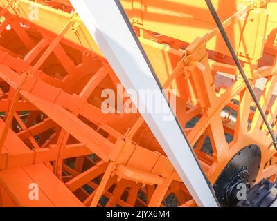 Old-fashioned waterwheel restored, maintained and painted yellow close up. Stock Photo