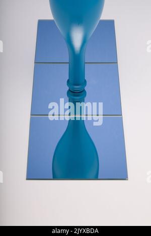 Horizontal image of mirror with reflection blue bottle in blue mirror. Concept of wine products. Stock Photo