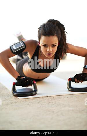 The ultimate upper body workout. a young woman exercising using push up grips. Stock Photo