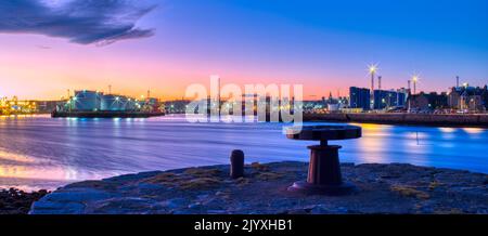 A panoramic view of Aberdeen Harbour from Torry, Aberdeen at night. In the foregroung can be seen a capstan and bollard on a disused quay. Stock Photo