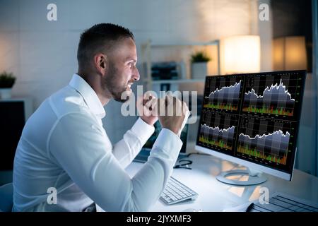 Successful Stock Market Trader Looking At Graphs On Multiple Screens In Office Stock Photo