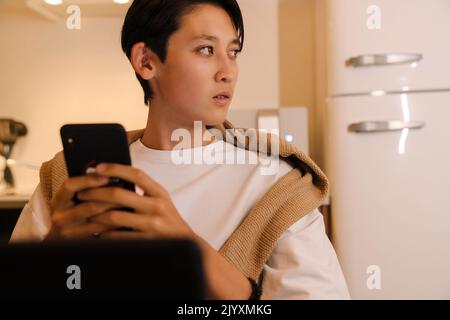 Asian boy using tablet computer and tablet computer in kitchen at home Stock Photo