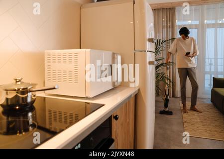 Asian boy using mobile phone while doing housework at home Stock Photo