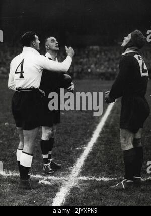 Rugby England win test by a point. England beat Australia by 5 points to 4 in the first Rugby League test match at Headingley, Leeds. Australia win the toss, (left to right) Gus Risman (English Captain), Mr. A.E. Harding (Referee) and W. Prigg the Australian Captain. An inspiring captain, Risman (left) tosses with Wally Prigg. Gus Risman tossing before the first England-Australia League test at Headingley in 1937. Australian captain Wally Prigg watches the coin in air. October 16, 1937. (Photo by Sport & General Press Agency, Limited). Stock Photo