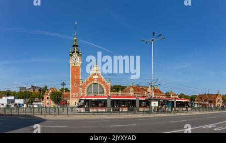 A picture of the Gdansk Main Train Station as seen through the other side of the avenue, with a tram stopped in the center. Stock Photo