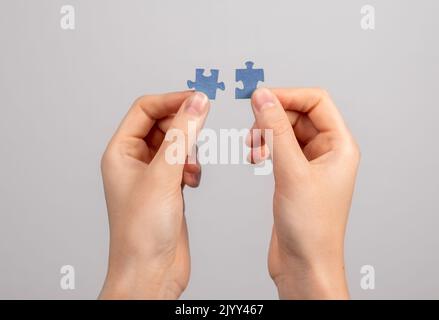 Hands connecting matching jigsaw puzzle pieces. Two details representing companies merging, joint venture, partnership, solution finding. High quality Stock Photo