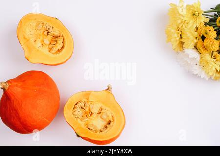 Orange pumpkins and yellow dahlia flowers on white background. Autumn concept. Top view, flat lay, copy space. Stock Photo