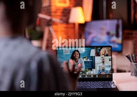 Businesspeople having conversation on online business meeting, telecommunications and remote teamwork concept. Businesswoman chatting with coworkers using videocall software and laptop, back view Stock Photo