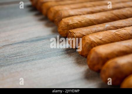 Cuban cigars on rustic wooden table in line on the edge of background. Stock Photo