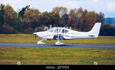 Light small plane flies against the background of a forest not high above the ground. Light aircraft on the air. A small tourist plane on an isolated Stock Photo