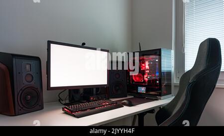 Powerful personal computer gamer rig with white screen. Professsional gaming empty room studio with neon lights and RGB powerful computer, keyboard an Stock Photo
