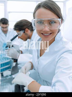 Investigator checking test tubes, Woman wears protective goggles Stock Photo