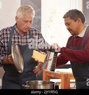 Its all about the cheese. two senior men cooking in the kitchen. Stock Photo
