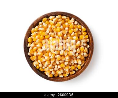 Dried corn kernels in wooden bowl placed on white background. Corn for popcorn. View from above. Stock Photo