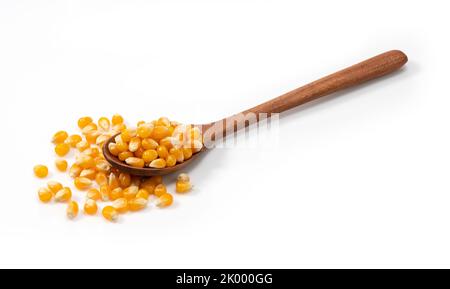 Dried corn kernels and wooden spoon placed on white background. Corn for popcorn. Stock Photo