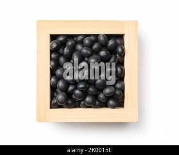 Black soybeans in a masu placed against a white background. Black