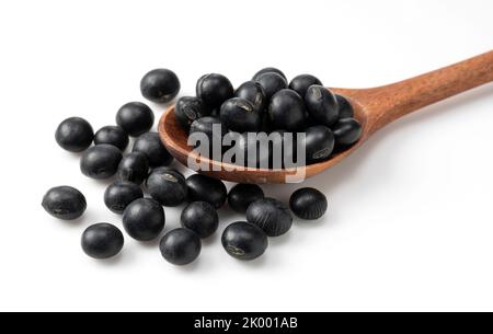 Black soybeans and a wooden spoon on a white background. Black soybeans. Stock Photo