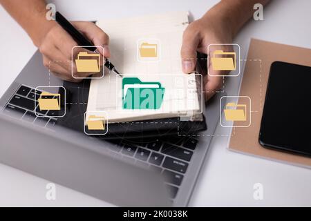 Paperless office concept based on e-documents. A businessman types on a laptop keyboard while viewing electronic document icons on a virtual screen. Stock Photo
