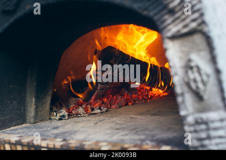 Wood-fired pizza oven with birch logs for kindling. The fire burns and the  oven heats up. Front view Stock Photo - Alamy