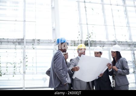 From design ideas to architectural reality. A diverse group of architects looking over blueprints together with copyspace. Stock Photo
