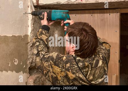 Drilling a hole in a concrete wall with a punch Stock Photo