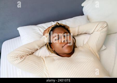african american woman trying to sleep but headache makes it difficult Stock Photo