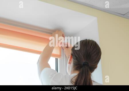 Female hands installing roller blinds on the window. Installation of roller blinds Stock Photo