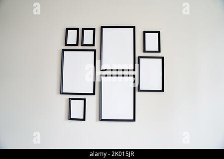 Different size framed photos hanging on the gray wall. Mockup. Stock Photo