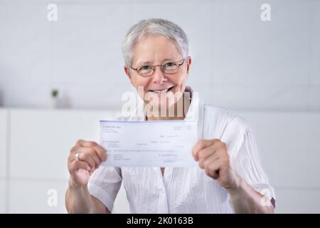 Holding Paycheck Or Payroll Check Or Insurance Cheque In Hand Stock Photo
