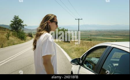 Man stands on the road next to his car  Stock Photo
