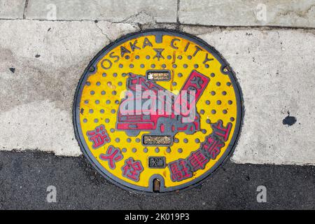 A manhole cover showing a fire truck in the city of Osaka, Japan. Stock Photo