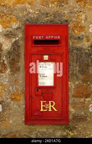 Queen Elizabeth II postbox. Red paint with Gold lettering. Set in a stone wall. Royal Mail. Stock Photo