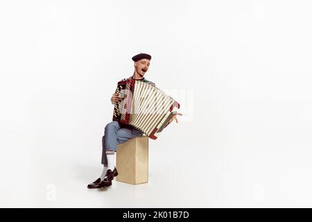 Portrait of young man playing accordion, posing isolated over white studio background. Positive music Stock Photo