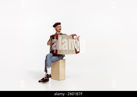 Portrait of young emotive man playing accordion, posing isolated over white studio background Stock Photo