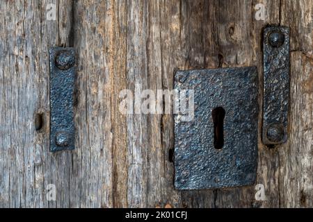 Antique church iron door furniture keyhole on a bleached oak door with rusting studs Stock Photo