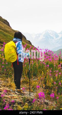 Young fit happy woman stand on viewpoint after reach top in mountains. Carefree tourist woman looking at sun enjoying landscape. Girl traveler on top Stock Photo