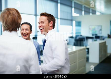 Friendly business people. Handsome business man having friendly conversation with colleagues during break. Stock Photo