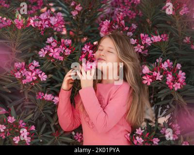 girl in a summer field sniffs a bouquet of flowers. Sunny day, holidays, allergy to flowering, freedom. Copy space Stock Photo