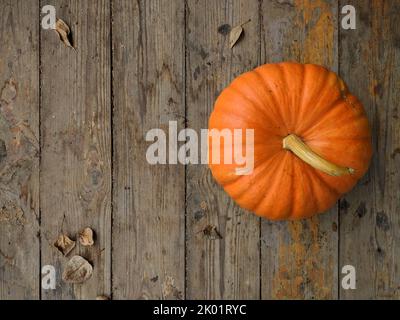 Fresh pumpkin and autumn leaves on aged wooden table. Haloween or food background.  Stock Photo