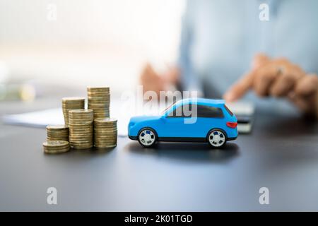 Blue Toy Car In Front Of Businesswoman Calculating Loan Stock Photo