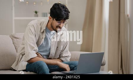Ill arabic man bearded guy with glasses feels stress overwork cranial pressure massages weight on head suffering from headache migraine sighing Stock Photo