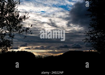 Dramatic sky before sunset framed by the silhouettes of trees Stock Photo