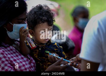 small child holding a pencil while mom is carrying in hand in Sri Lanka 30th July 2022 Stock Photo