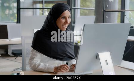 Excited arab businesswoman feeling winner celebrating success rejoicing in victory looking at computer screen winning online video game overjoyed girl Stock Photo