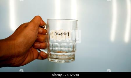 close up hand holding empty drinking glass with text word drink written on duct tape Stock Photo