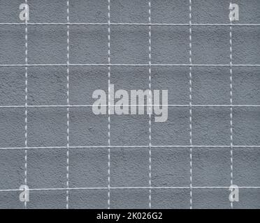 a metal grid and a gray wall behind it Stock Photo